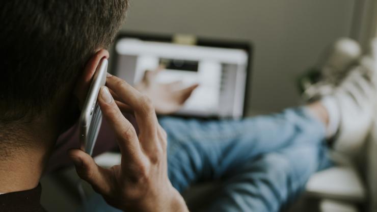 Jeune homme parlant dans un mobile devant un ordinateur